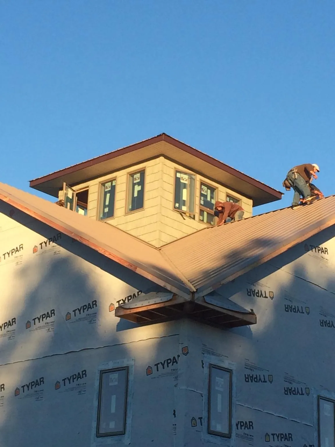 Roofers working around a rooftop cupola on a new metal roof at sunset — Roof Waterproofing in Empire by Roofing Brothers